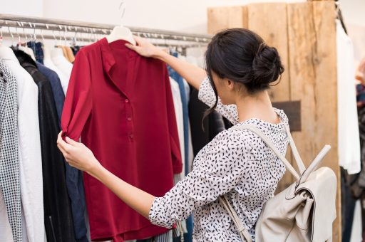 Woman choosing blouse from new collection of clothes in a boutique.